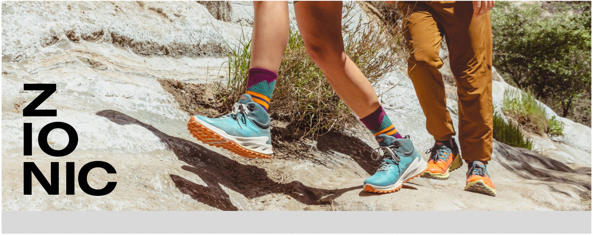 Man and woman wearing blue and orange Zionics hiking up rocky path