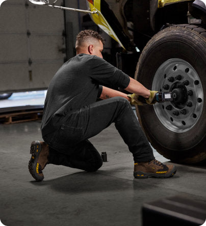 A man removing a large tire from a vehicle.