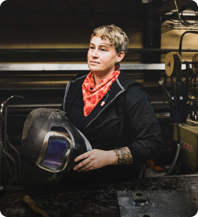 A woman working on a job site, holding a protective helmet.