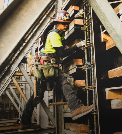 A woman working on a job site, wearing a pair of KEEN work boots.