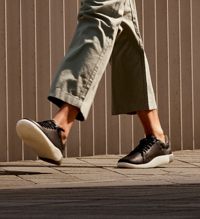 A person walking outside in a pair of black KEEN KNX casual sneakers.
