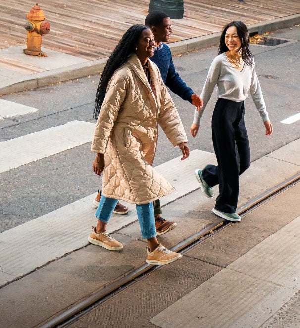 Two women and one man wearing wk400 walking shoes walking across a city street-crossing