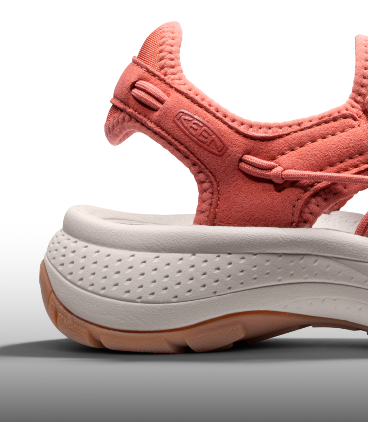 A close-up of the sole of a coral and white KEEN sandal.